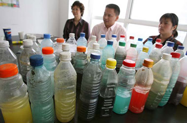 Beijing, China: Xu Jiehua (r), the wife of the detained Chinese environmental activist Wu Yilong, sits behind water samples collected by Wu Yilong from Chinese urban rivers and lakes.