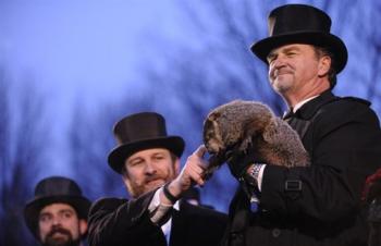 Groundhog handler Ben Hughes pets Punxsutawney Phil, while co-handler John Griffiths holds him